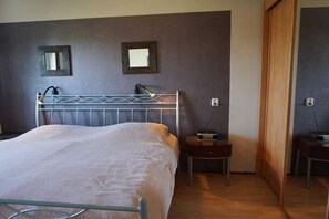 A bedroom with a metal bed frame, two bedside tables, a nightstand, and a wooden door. - Residence Juliana 47 (Julianadorp)