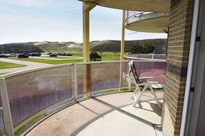 A balcony with a view of a parking lot and hills. - Residence Juliana 47 (Julianadorp)