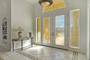 A room with a tiled floor, a console table with a lamp, and a large door with frosted glass panels. - CCVS - Dream Villa Mango Bay (Cape Coral)