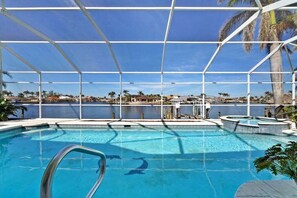 Ein Pool mit klarem, blauem Wasser, umgeben von einem weißen Zaun und Palmen im Hintergrund.
