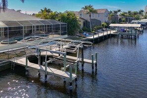 A waterfront property with a swimming pool, dock, and covered areas. - CCVS - Dream Villa Mango Bay (Cape Coral)