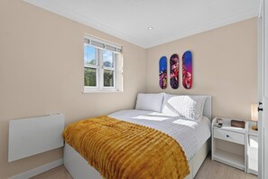 A bedroom with a bed, a window, and a wall-mounted artwork. - New! Stylish 1BR Flat in Lewisham (Greater London)