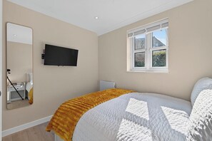 A bedroom with a bed, a television, a window, and a mirror. - New! Stylish 1BR Flat in Lewisham (Greater London)