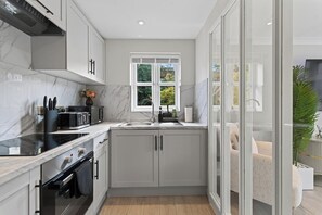 A modern kitchen with a built-in oven, microwave, and sink. - New! Stylish 1BR Flat in Lewisham (Greater London)