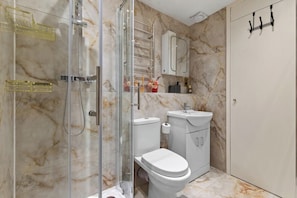 A modern bathroom with a glass-enclosed shower, a toilet, a sink, and a cabinet. - New! Stylish 1BR Flat in Lewisham (Greater London)
