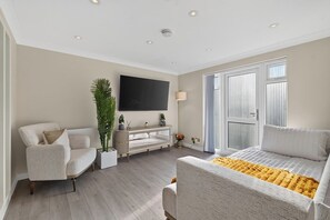 A modern living room with a sofa, armchair, and a television. - New! Stylish 1BR Flat in Lewisham (Greater London)