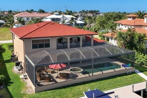 Ein Haus mit rotem Ziegeldach, einem überdachten Pool und einer Terrasse mit Gartenmöbeln.