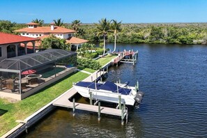 A waterfront property with a dock, a covered outdoor seating area, and a pool. - CCVS - Villa Kara Tuscany (Cape Coral, FL)