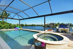 A swimming pool with a hot tub, surrounded by a covered area with a view of the water. - CCVS - Villa Kara Tuscany (Cape Coral, FL)