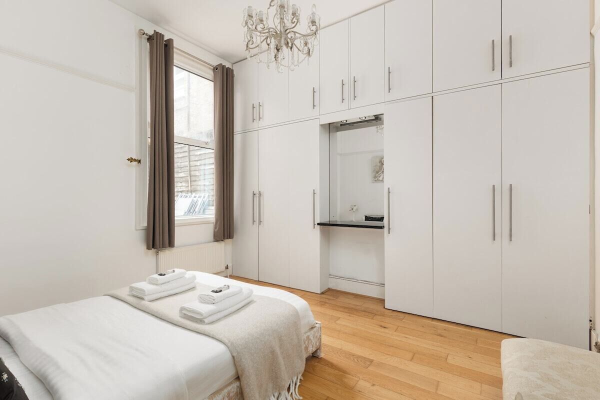 Een slaapkamer met een bed, een kledingkast, een spiegel en een kroonluchter.