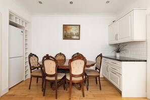 A dining area with a wooden table and chairs, white cabinets, and a potted plant. - New! Charming 1BR Maisonette | Alexandra Park (Greater London)