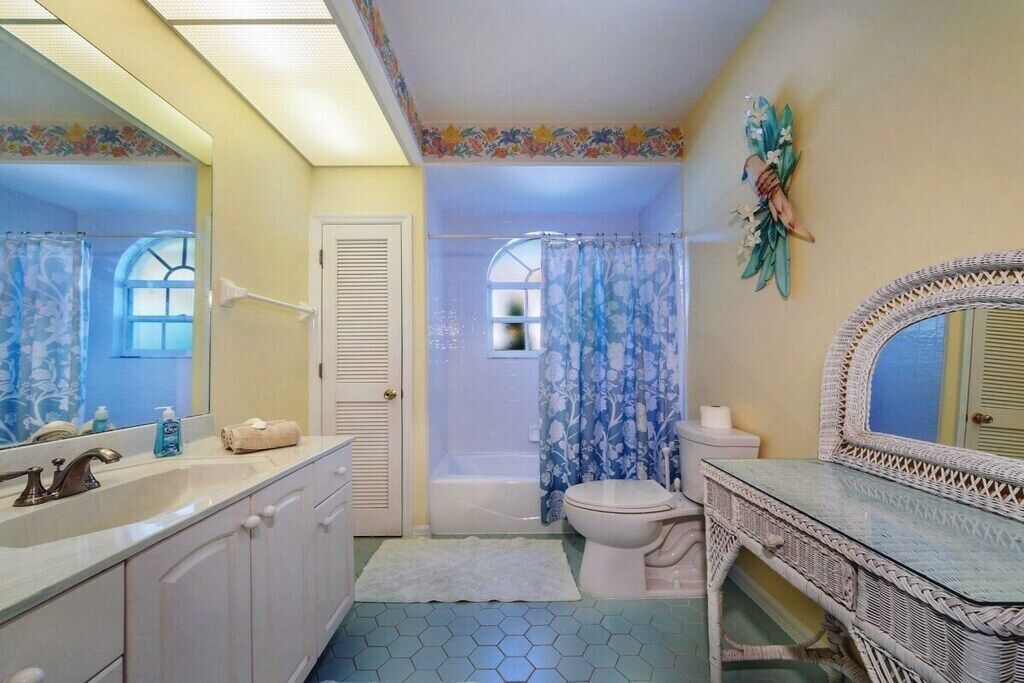 Ein Badezimmer mit Waschbecken, Spiegel, Toilette und Duschbereich.
