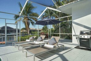 A sunlit outdoor lounge area with lounge chairs and a grill. - CCVS - Villa White Diamond (Cape Coral)