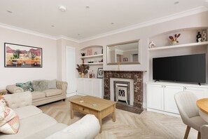Un salon comprenant un canapé, une table basse, une cheminée, un téléviseur et des objets de décoration.