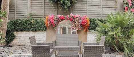 A patio with wicker furniture, a decorative archway, and a garden wall.