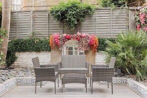 A patio with wicker furniture, a decorative archway, and a garden wall. - New! West Kensington 2BR Gem w/Garden & Patio (Greater London)