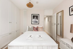 Un dormitorio con cama, armario, espejo y una foto enmarcada en la pared.