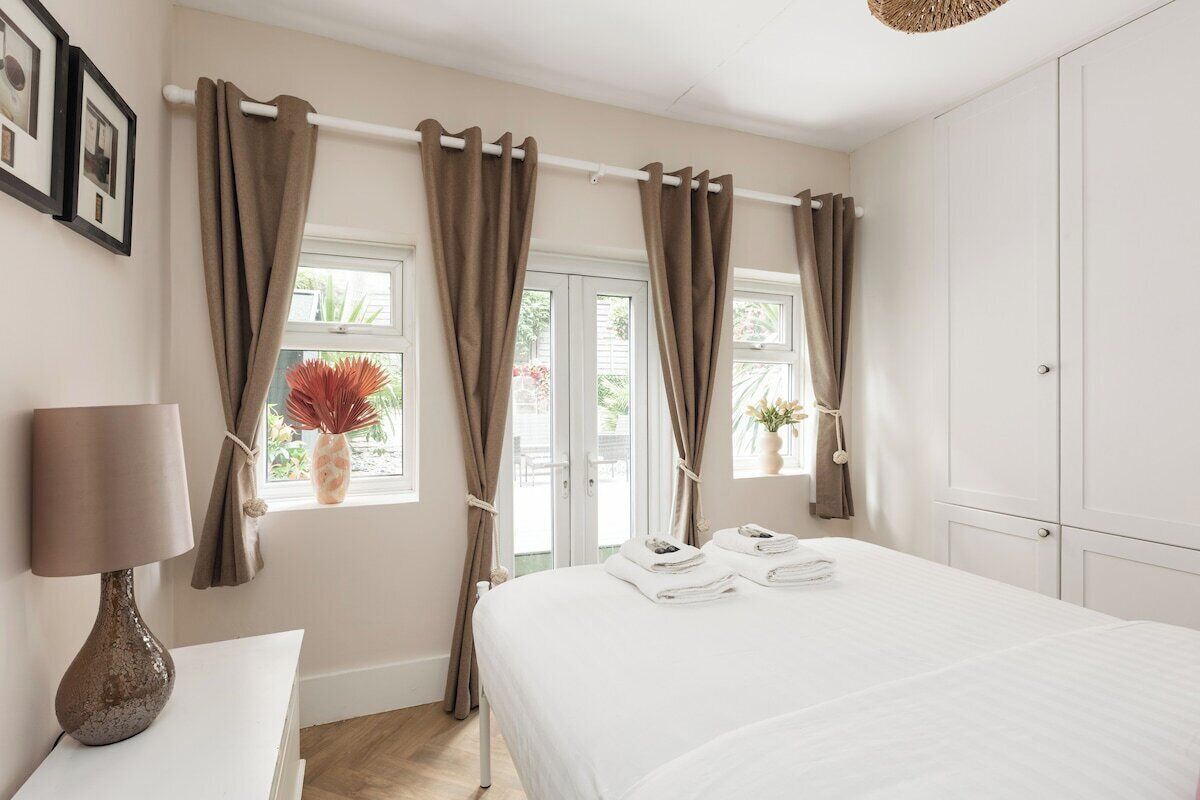 Une chambre à coucher avec un lit, des rideaux, une fenêtre, une lampe et une armoire.