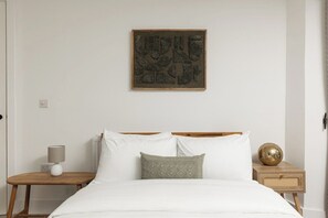 Een slaapkamer met een bed, een nachtkastje, een lamp, een decoratieve bol en een wanddecoratie.