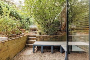 A garden with a wooden bench, steps leading to a raised bed, and a variety of plants. - New! Stylish 1BR Flat w/Patio in Vibrant Peckham (Greater London)