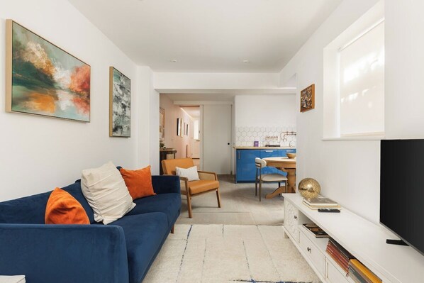 Ein modernes Wohnzimmer mit einem blauen Sofa, einem Fernseher und Kunstwerken an den Wänden.