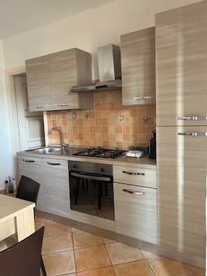 A modern kitchen with a gas stove, stainless steel appliances, and light wood cabinetry. - AGP Murta Maria Olbia Vacation Home (Sardegna)