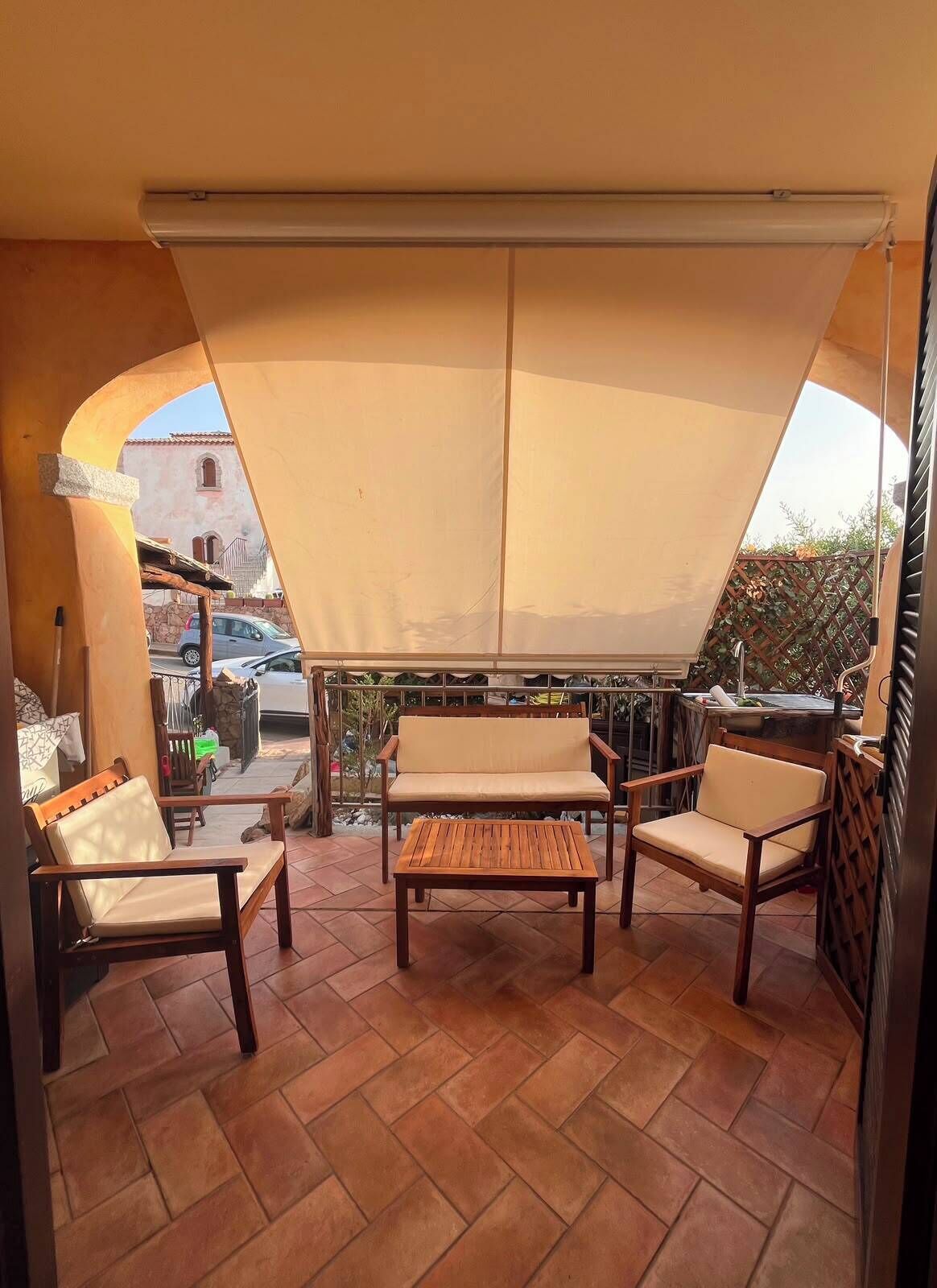Un patio al aire libre con un espacio de estar cubierto, una mesa de madera y una parrilla.