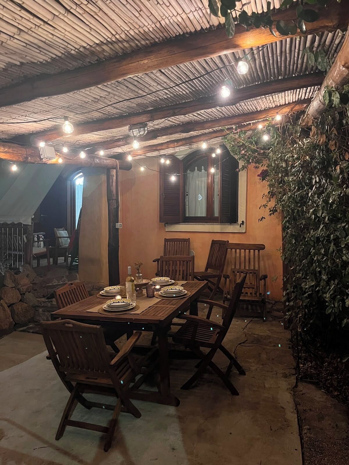 An outdoor dining area with a table set for four, surrounded by wooden chairs.