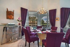 Ein Essbereich mit einem Glastisch, violetten Stühlen und einer Hängelampe.