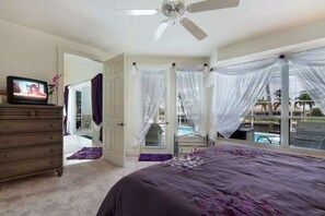 A bedroom with a bed, a dresser, a television, and a ceiling fan. - CCVS - Villa Dream Home (Cape Coral)