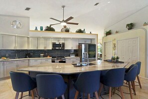 A modern kitchen with a central island, built-in appliances, and a ceiling fan. - CCVS - Villa Sunny Breeze (Cape Coral)