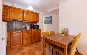 A kitchen with wooden cabinets, a microwave, a kettle, and a dining table with chairs. - Awesome apartment in Arta with WiFi (Arta)