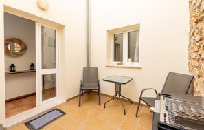 A small, enclosed outdoor area with a table and chairs, a window, and a door leading to an interior space. - Awesome apartment in Arta with WiFi (Arta)
