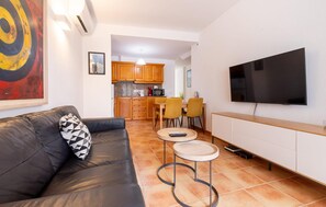 A living room with a sofa, a TV mounted on the wall, and a kitchen in the background. - Awesome apartment in Arta with WiFi (Arta)