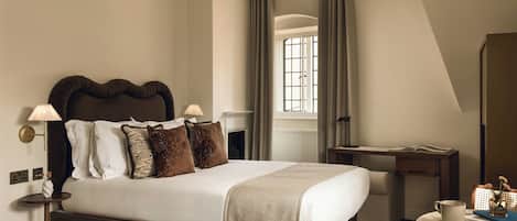 A modern bedroom with a large bed, bedside lamps, a desk, and a window with curtains.