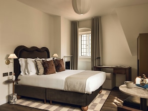 Un dormitorio moderno con una cama grande, lámparas de noche, un escritorio y una ventana con cortinas.