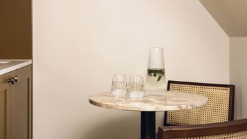 A round table with a marble top, two glasses, and a clear vase with a plant.