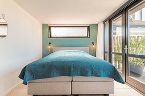 A bedroom with a bed, a window, and a view of greenery outside. - Holiday home in Alkmaar with barbecue (Alkmaar)