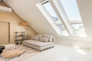 A modern loft bedroom with a sloped ceiling, a sofa bed, a floor lamp, and a large skylight. - Holiday home in Alkmaar with barbecue (Alkmaar)