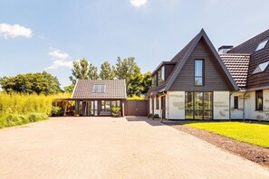 A modern two-story house with a paved driveway and a covered outdoor seating area. - Holiday home in Alkmaar with barbecue (Alkmaar)