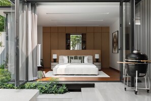 Une chambre moderne avec un grand lit, une porte vitrée donnant sur l’extérieur et un barbecue situé à l’extérieur de la pièce.