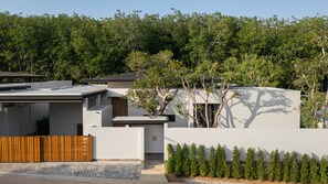 A modern residential building with a flat roof, a wooden fence, and a landscaped garden with neatly trimmed shrubs. - Layan - Private Designer Villa (Tambon Thep Krasatti)