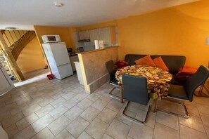 A dining area with a table set for two, a kitchen in the background, and a staircase leading to an upper level. - Jacky's Holiday Apartment 2 (Zinnowitz)