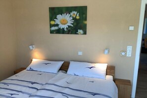 A bedroom with a bed, pillows, a nightstand, a wall-mounted light, and a wall decoration. - Holiday apartment in Butjadingen with Wi-Fi (Butjadingen)