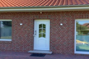 A brick building with a white door, two windows, and a red-tiled roof. - Holiday apartment in Butjadingen with Wi-Fi (Butjadingen)