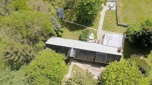 An aerial view of a building with a flat roof, surrounded by dense greenery.