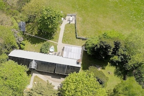 A large building with a flat roof, surrounded by trees and a grassy area.