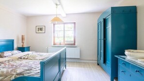 A bedroom with a bed, dresser, window, and radiator.