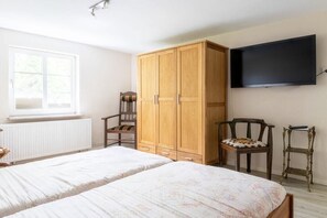 Une chambre à coucher avec un lit, une armoire, une chaise et un téléviseur fixé au mur.