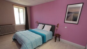 Quarto com cama, janela, radiador e um quadro na parede.